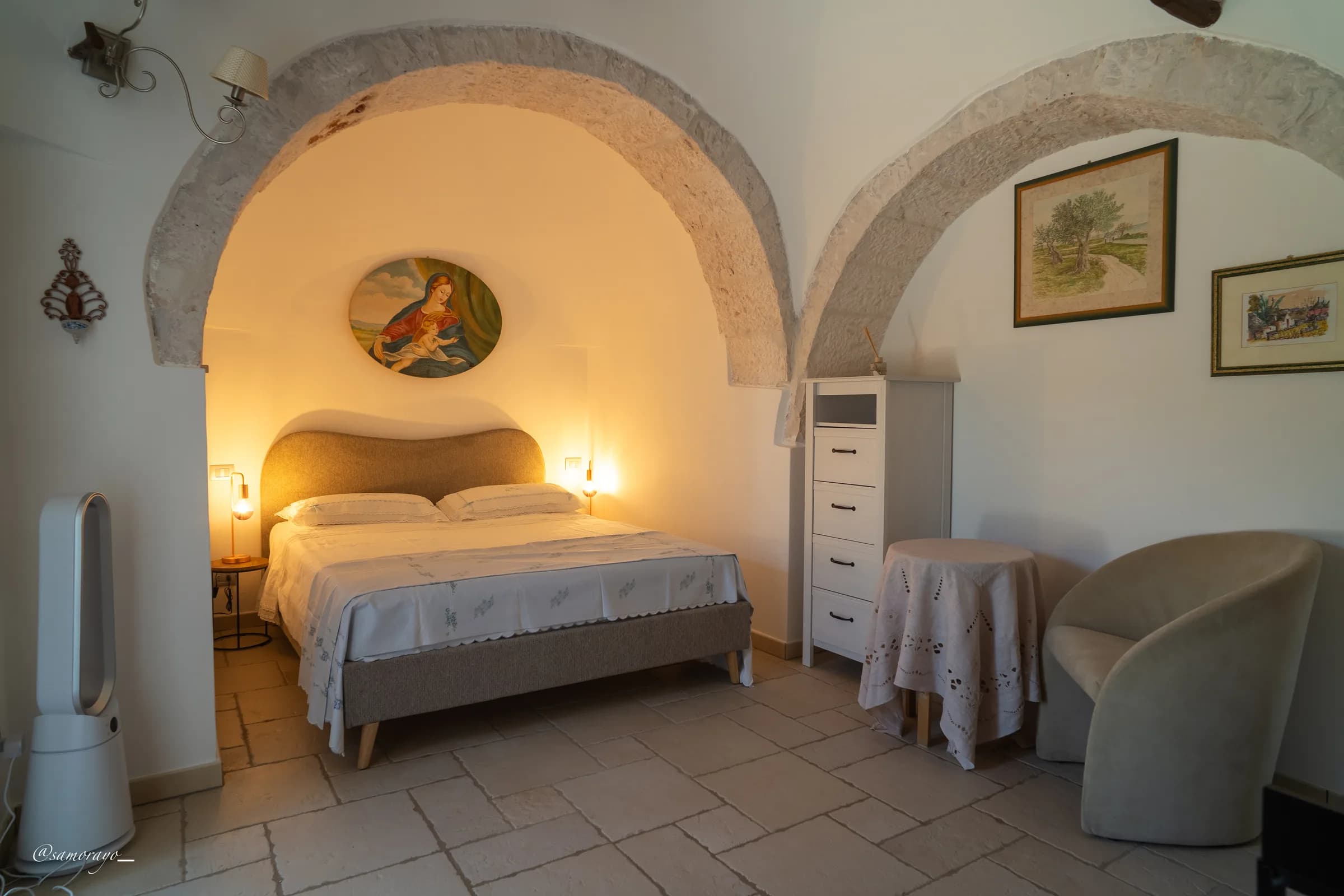 Angolo con cassettiera e TV sotto l'arco in pietra