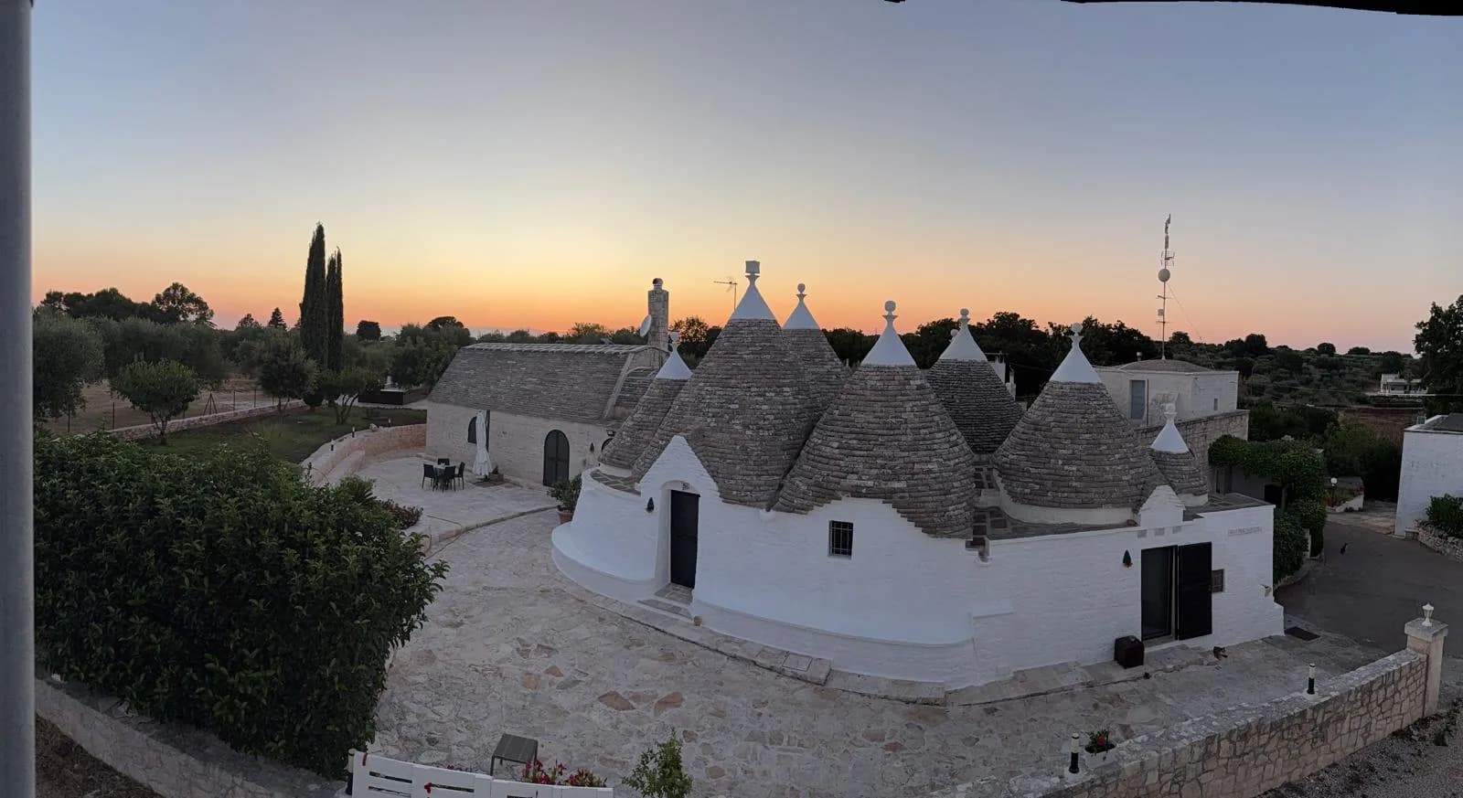 Panoramica dei trulli e del giardino al tramonto